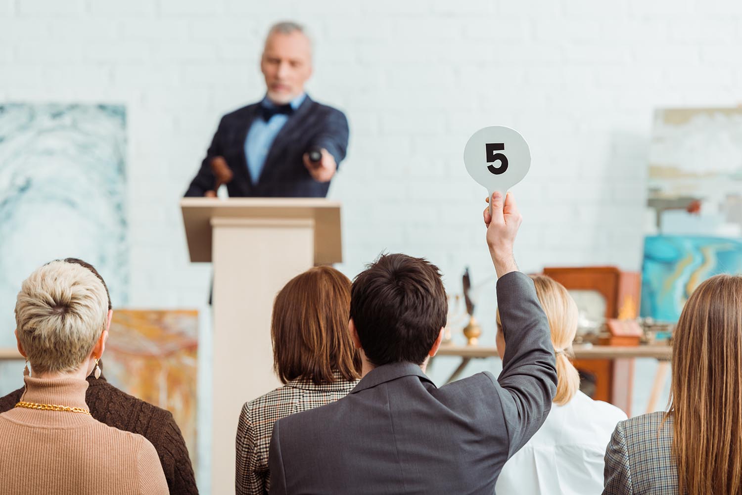man holding up card at an auction
